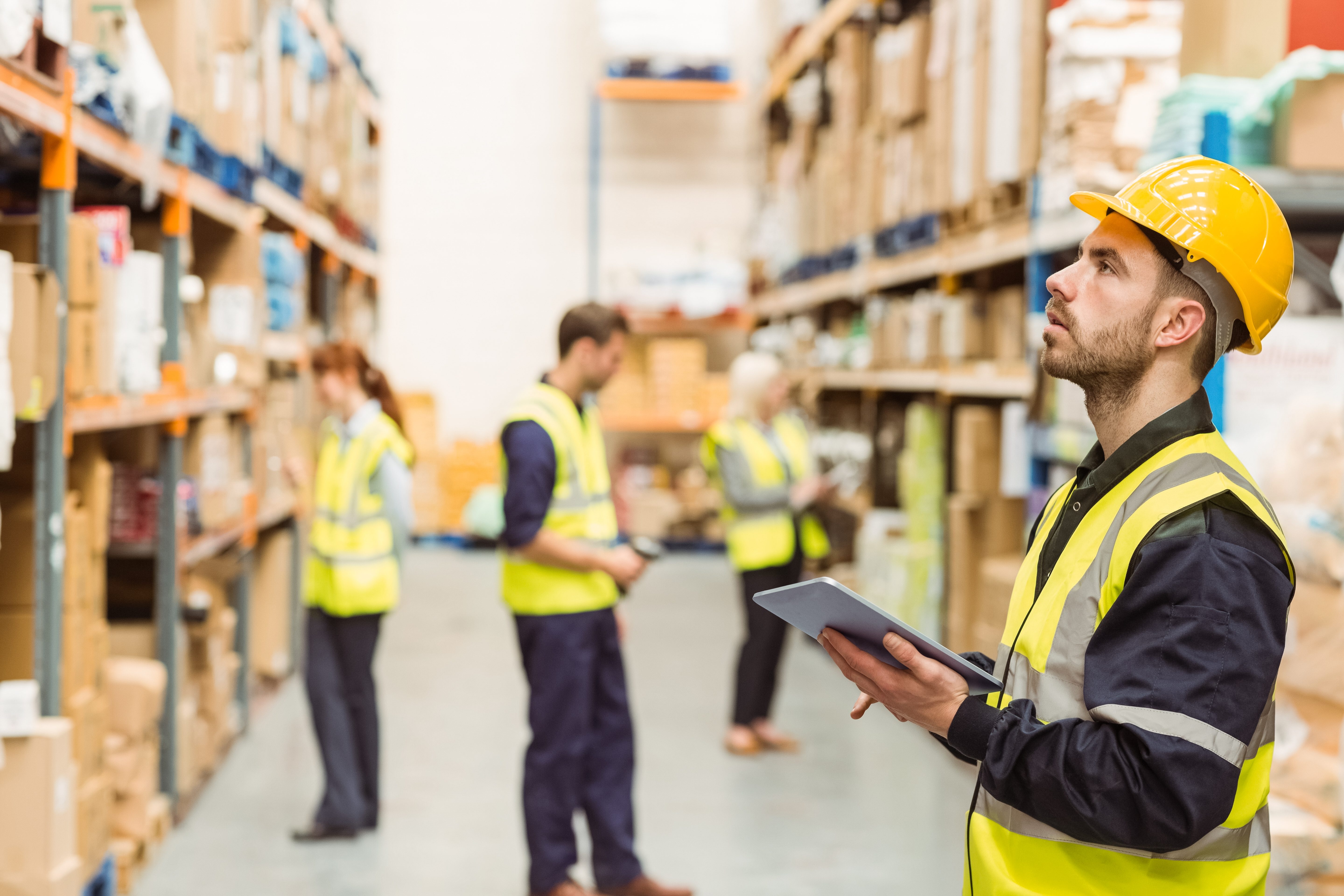 Focused warehouse manager writing on clipboard in a large warehouse.